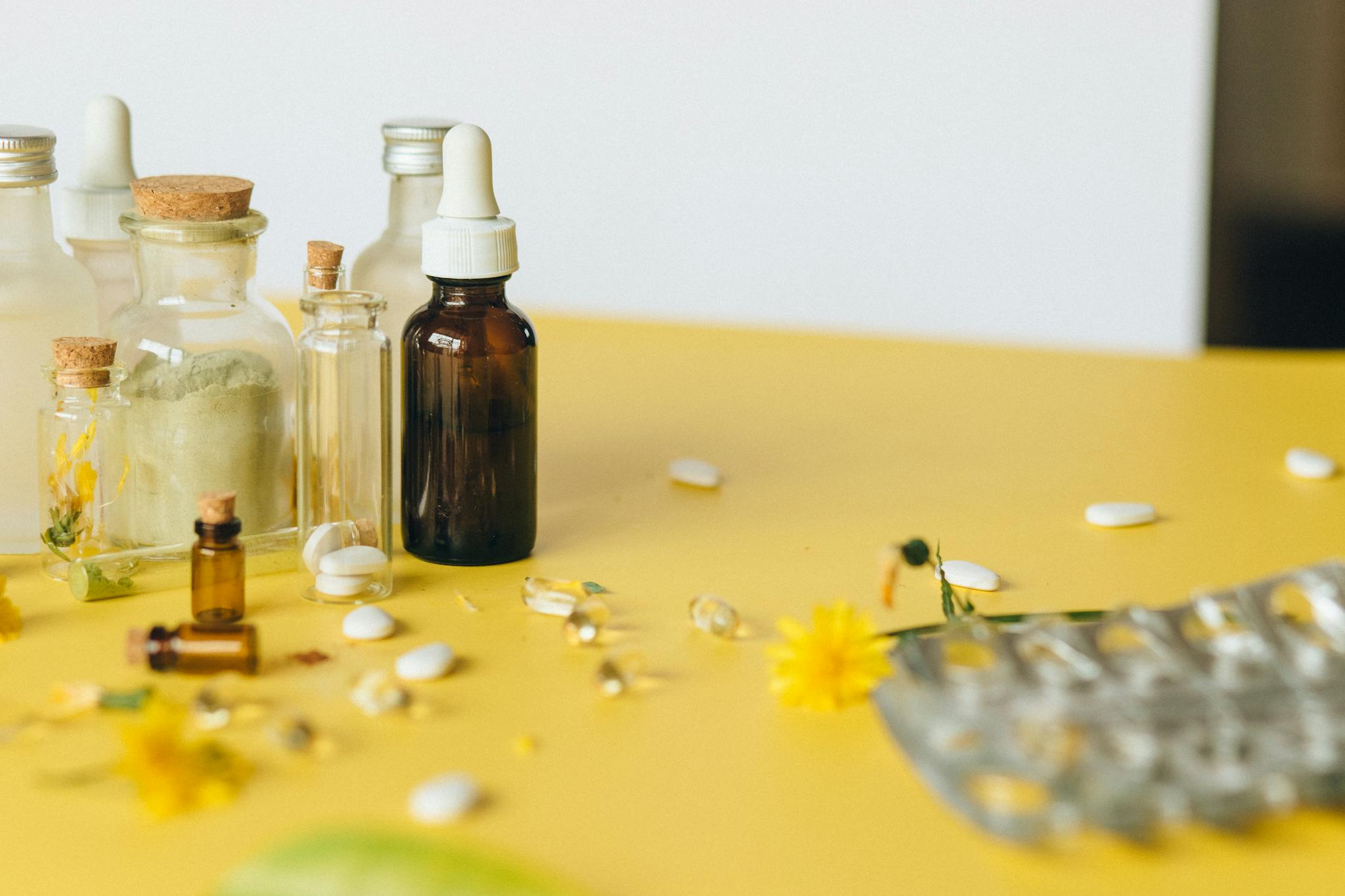 Assorted bottles and capsules on a yellow surface, highlighting natural remedies.